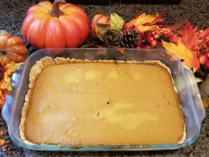 Pumpkin Pie Bar in a Pyrex Rectangular Baking Dish adorned with pumpkin decor and vibrant fall leaves