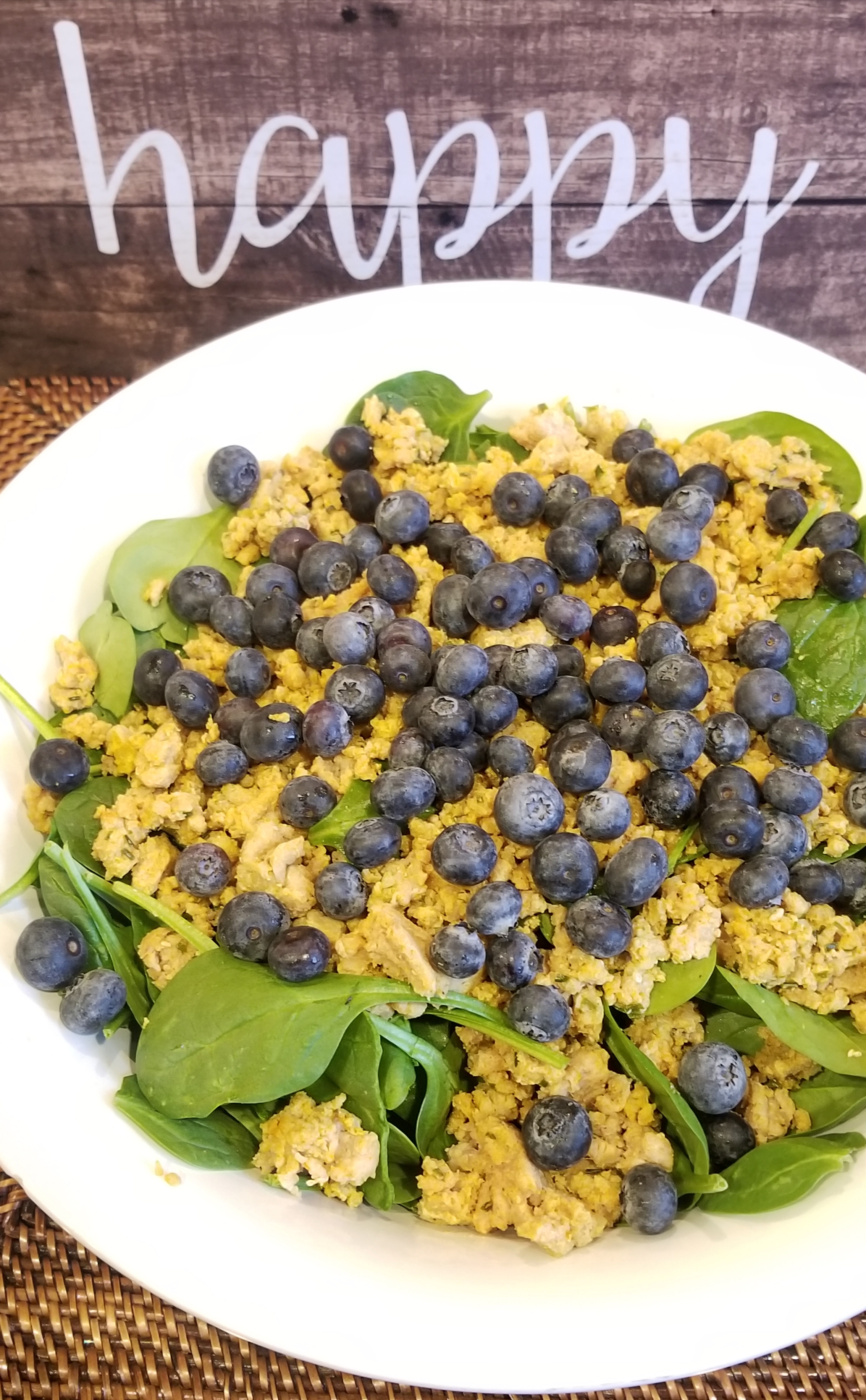 Bowl of Green Spinach topped with ground turkey and blueberries