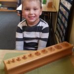 Smiling Ayden Sorting Peg Cylinders into their proper sized hole in wood block at school 3