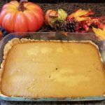 Pumpkin Pie Bar in a Pyrex Rectangular Baking Dish adorned with pumpkin decor and vibrant fall leaves